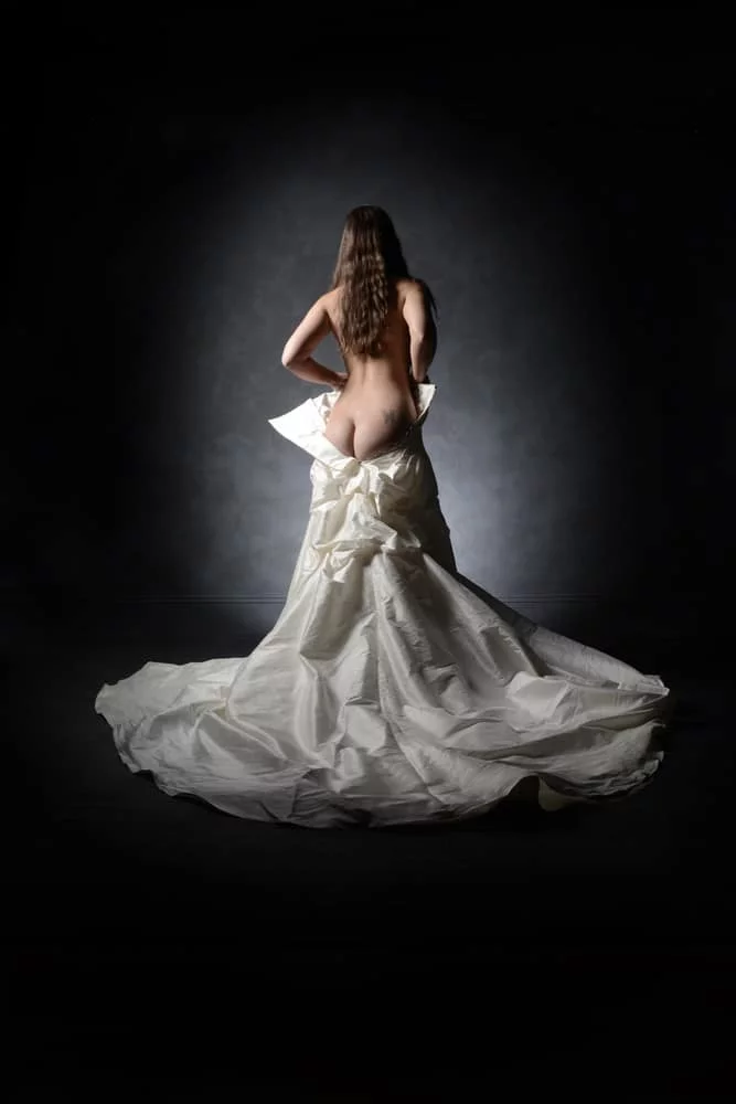 bridal boudoir image of a bride almost wearing her wedding dress