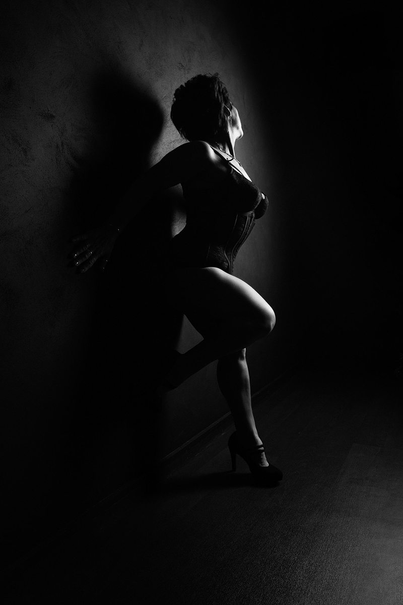 black and white boudoirimage of a woman leaning against a wall