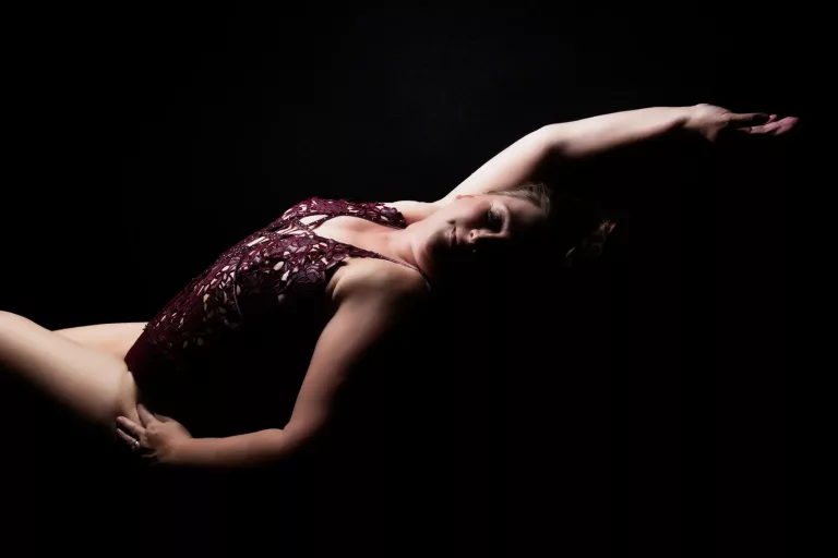 flattering boudoir pose for a woman wearing a burgundy lace body