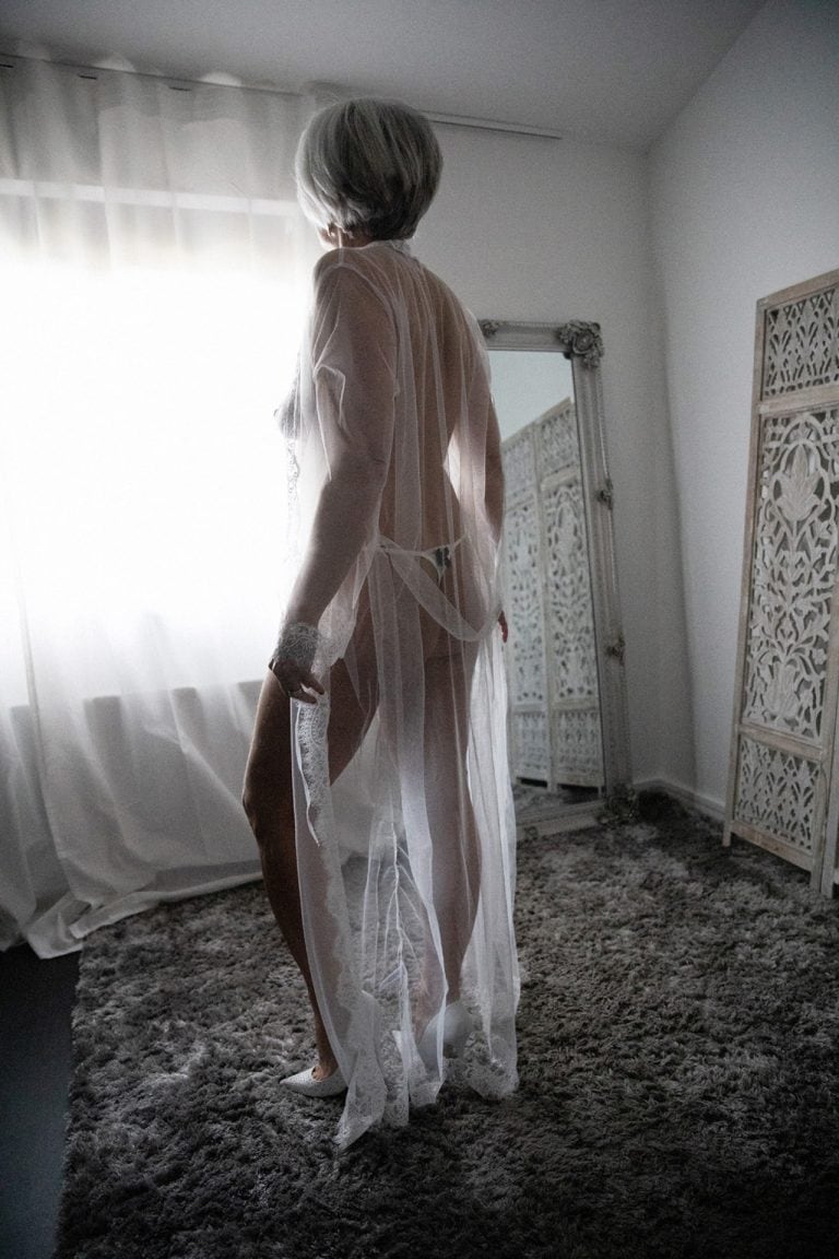 stunning 60 year old woman wearing a white lace robe