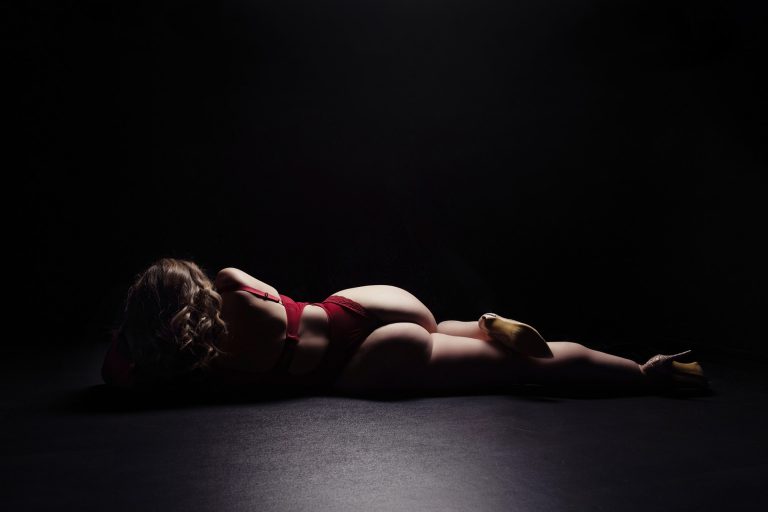 reclining boudoir pose of a woman wearing a red body