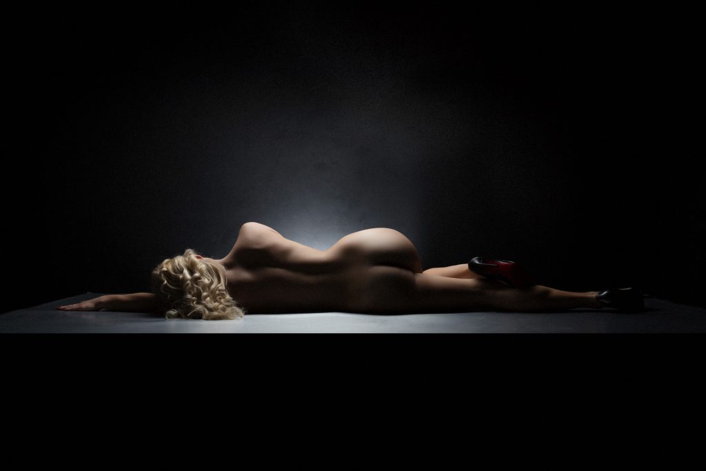 nude woman laying on her side lit with dramatic lighting