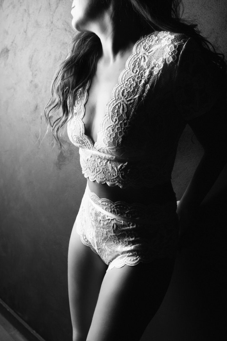black and white image of a woman wearing a lacy white lingerie outfit